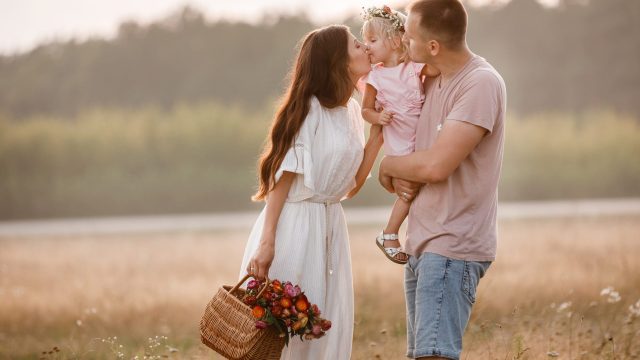 Portrait of happy family. Mom, dad and daughter walk in the field. Young family spending time